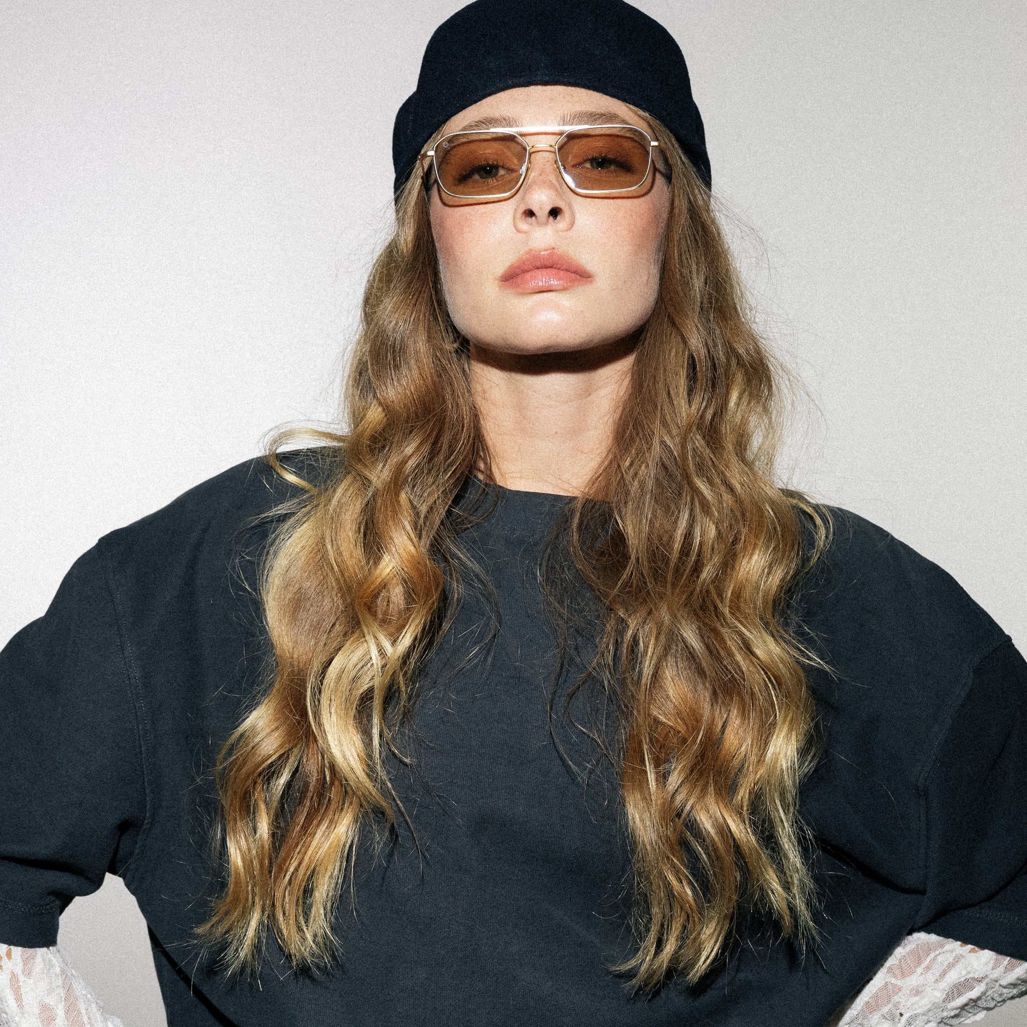 Person wearing sunglasses and a black beanie against a plain background