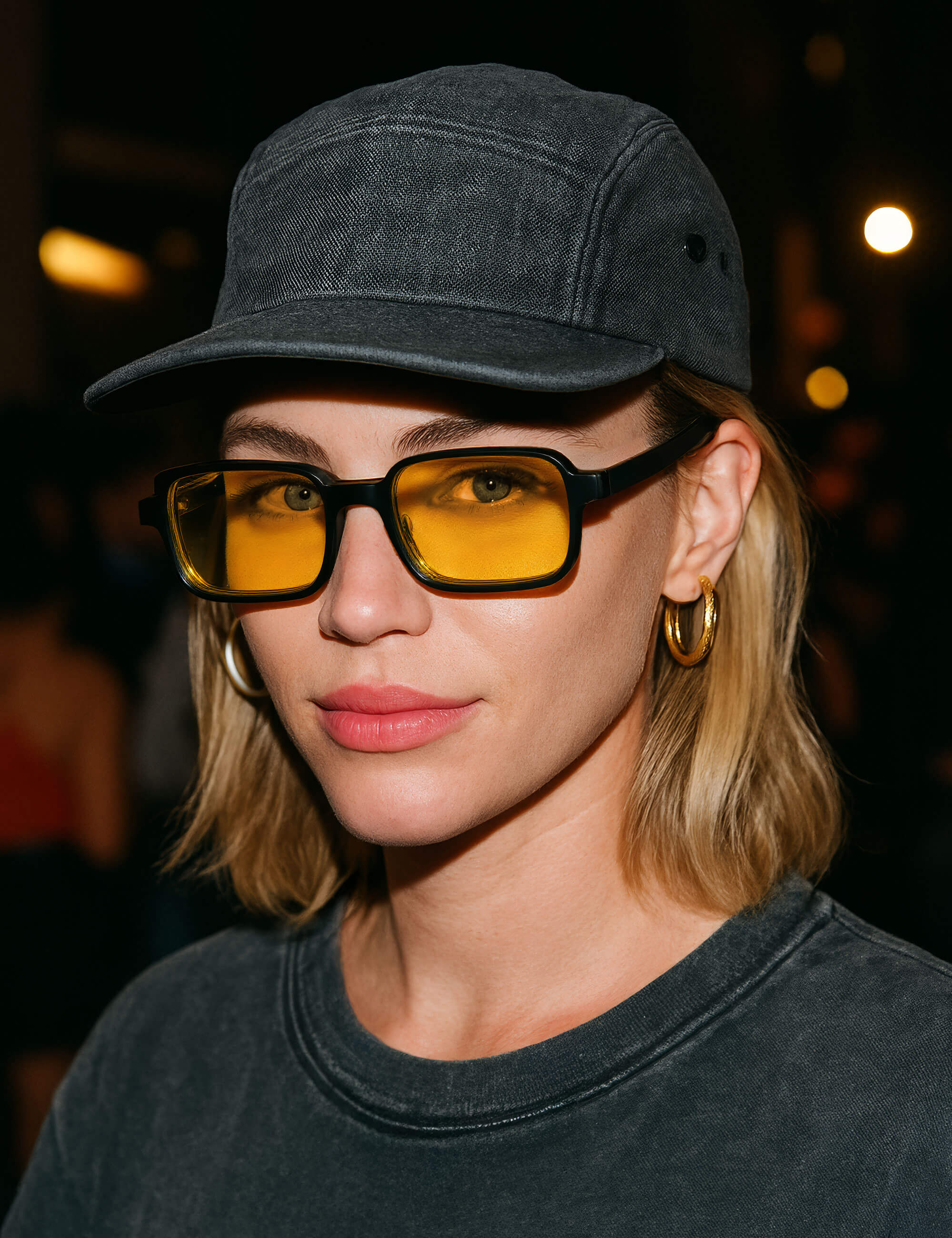 Person wearing a dark cap and sunglasses with a blurred background
