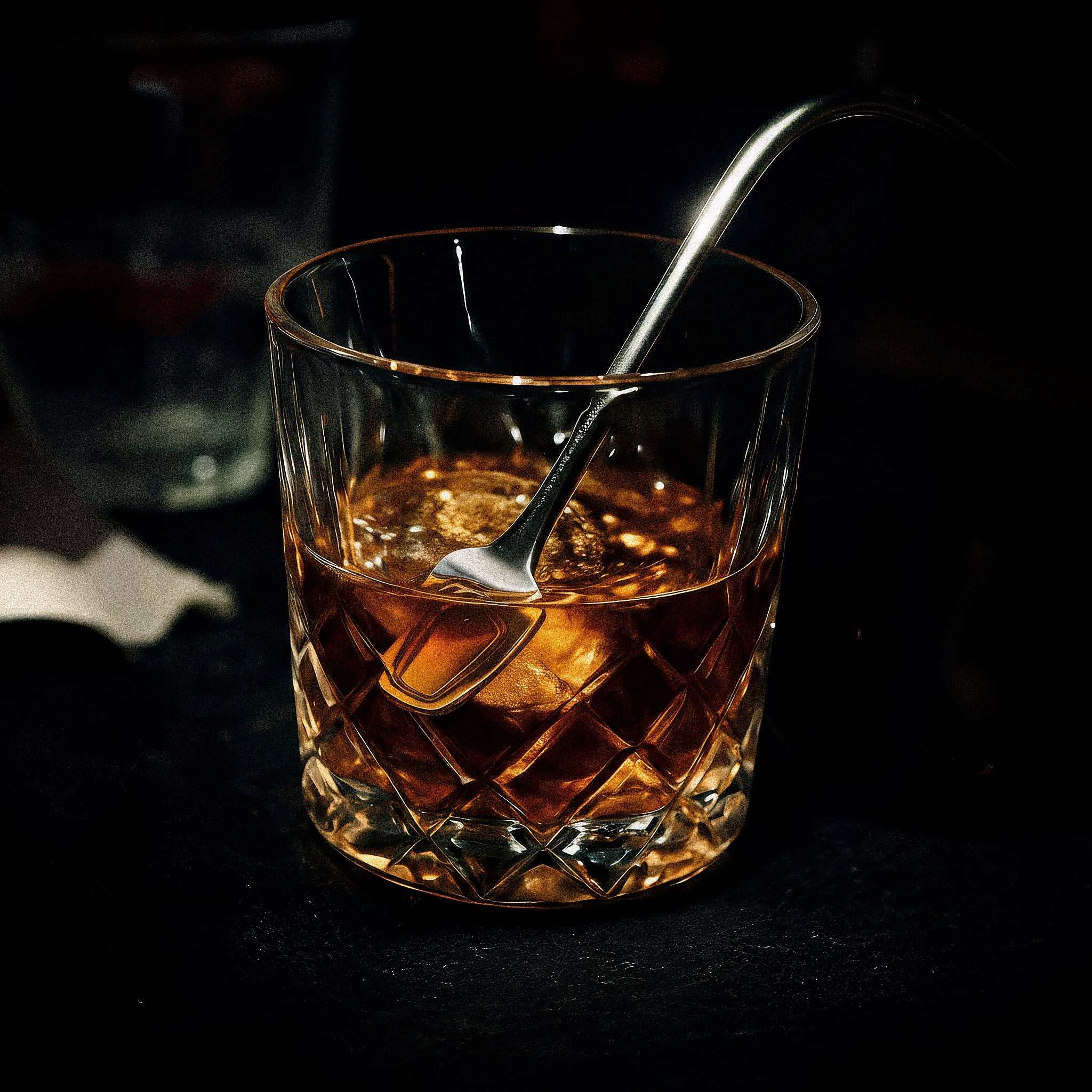 Glass of whiskey with a spoon on a dark background